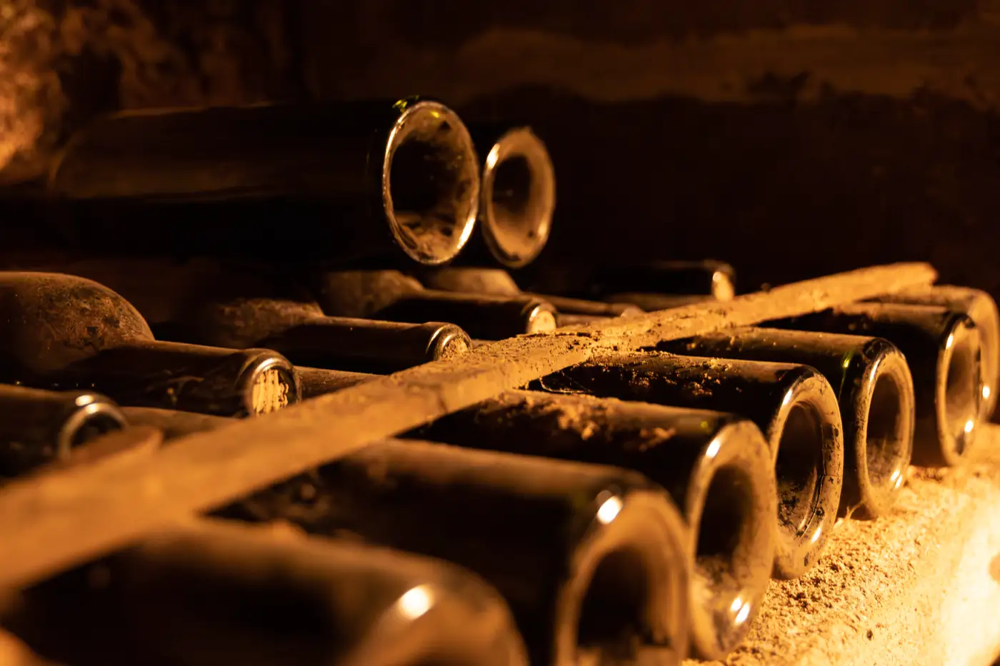 Bouteilles poussiéreuses vieillissant couchées dans une cave.