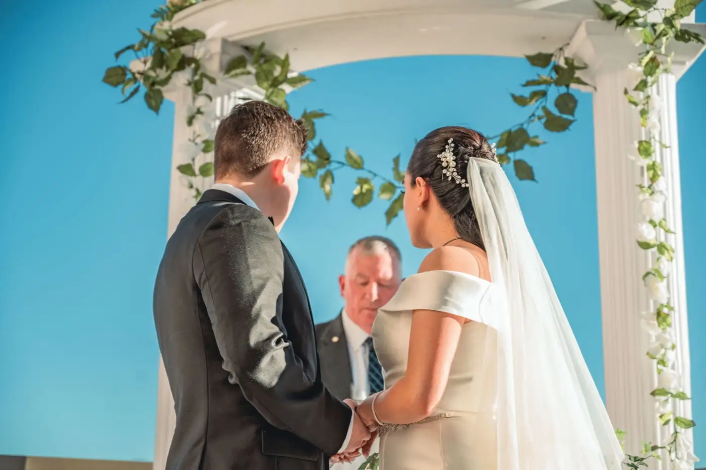 Une cérémonie de mariage en plein air, sous une arche fleurie.