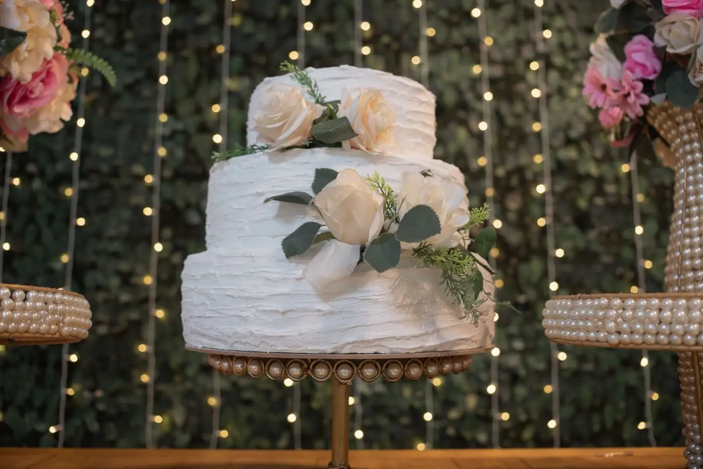 Une pièce montée de mariage devant un rideau de lumières.