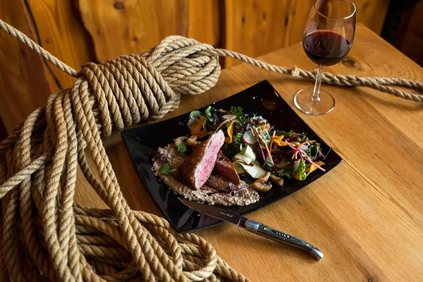 Un plat de gibier servi avec un verre de vin.